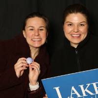 two friends smiling with the laker for a lifetime sign at GradFest